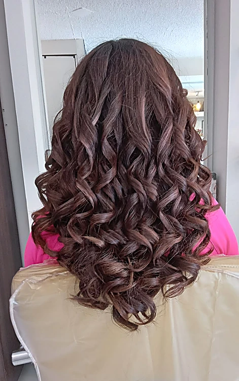 Cabello castaño largo peinado en rizos definidos, visto de espaldas en el sillón.